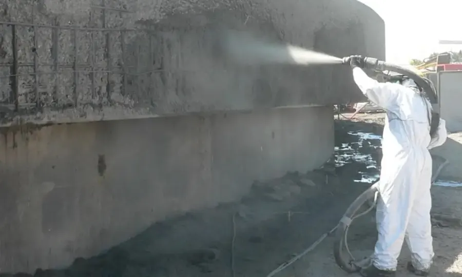 Technician abrasive blasting a concrete structure in preparation for remediation